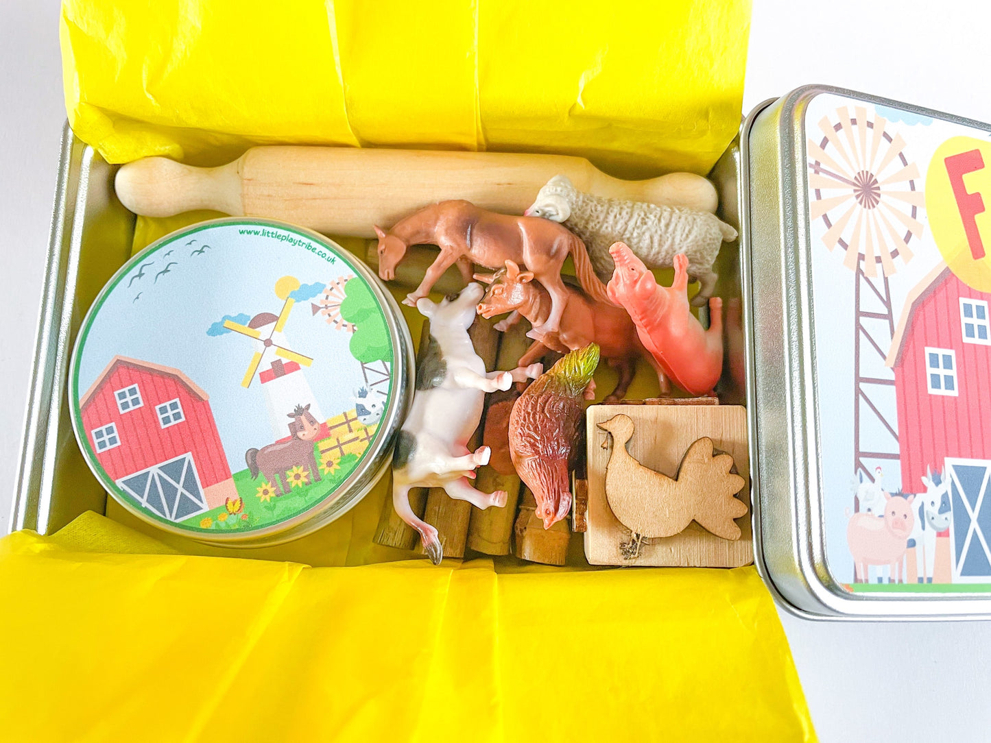 Farm Dough on the Go Activity Play Tin filled with Green Grass Farm Playdough, Farm animals for play scened, farm themed stamper and playdough tools and accessories wooden rolling pin. All wrapped up in a reuable metal tin with Farm stickers and wrapped in yellow tissue paper perfect for gifting.