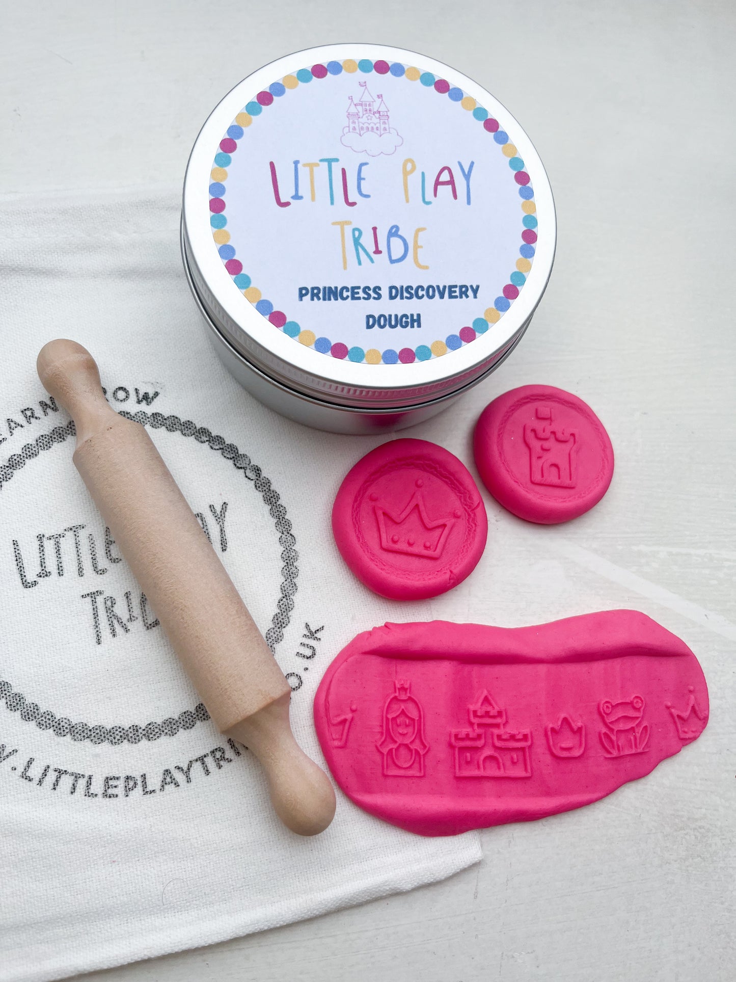 Pink Playdough in 250g maxi tub size in princess theme with hidden princesses, topped with a gold glitter crown. Shown as a grab and go dough set with Little PlayTribe Bag, Eco Princess Roller and Wooden Rolling Pin for Playdough accessories and dough tools. Playdough Kit