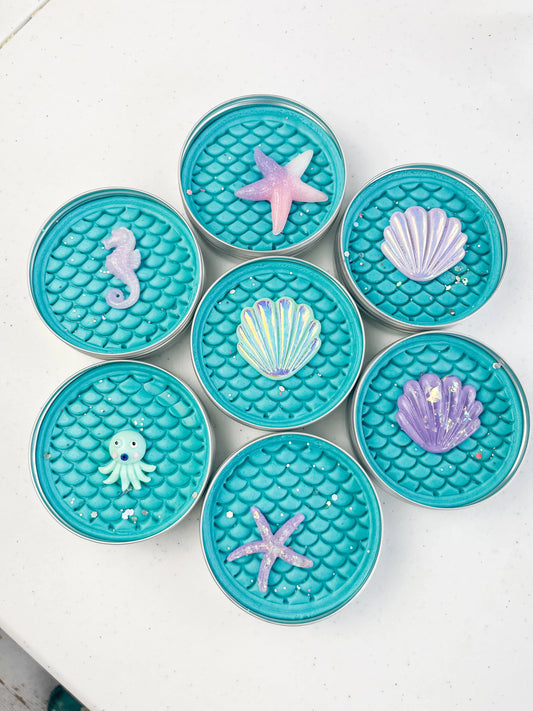Tins of Blue playdough with mermaid scale inprint for mermaid and under the sea themed kids birthday party favours. Alternative party bag filler with under the sea resin charms