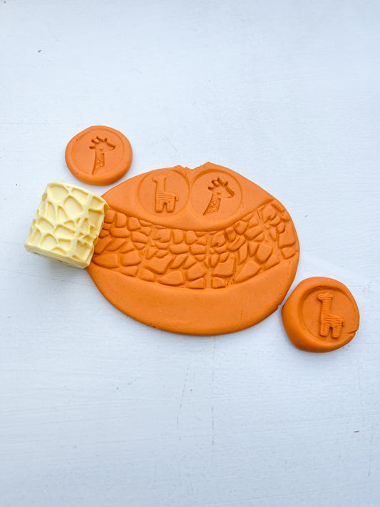 plastic free eco roller with safari themed imprints showing animal themed shapes on orange playdough with this tool