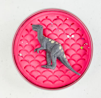 Pink playdough tin with a gray dinosaur toy on a white background