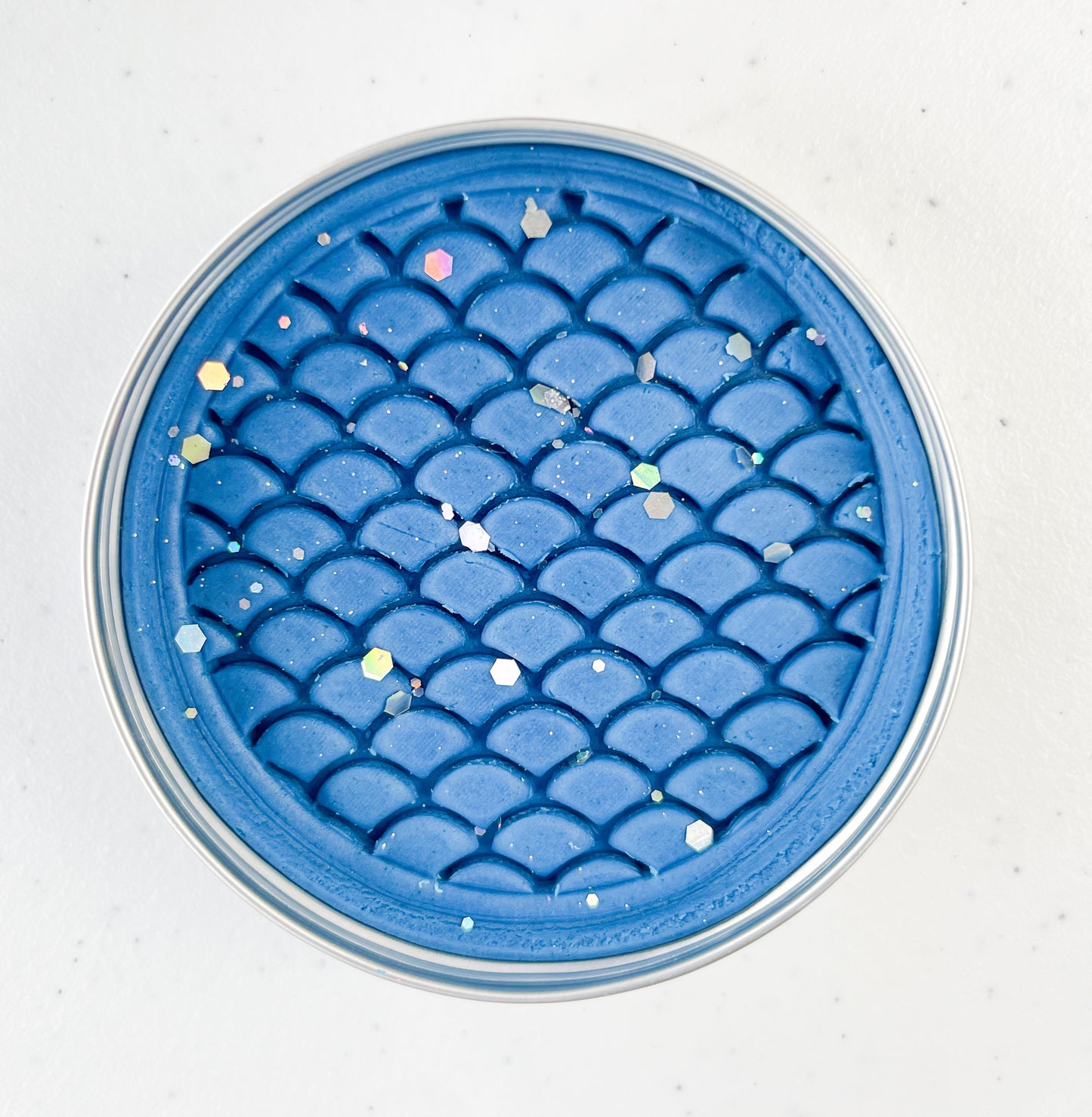 Blue textured dinosaur themed playdough tin on a white background