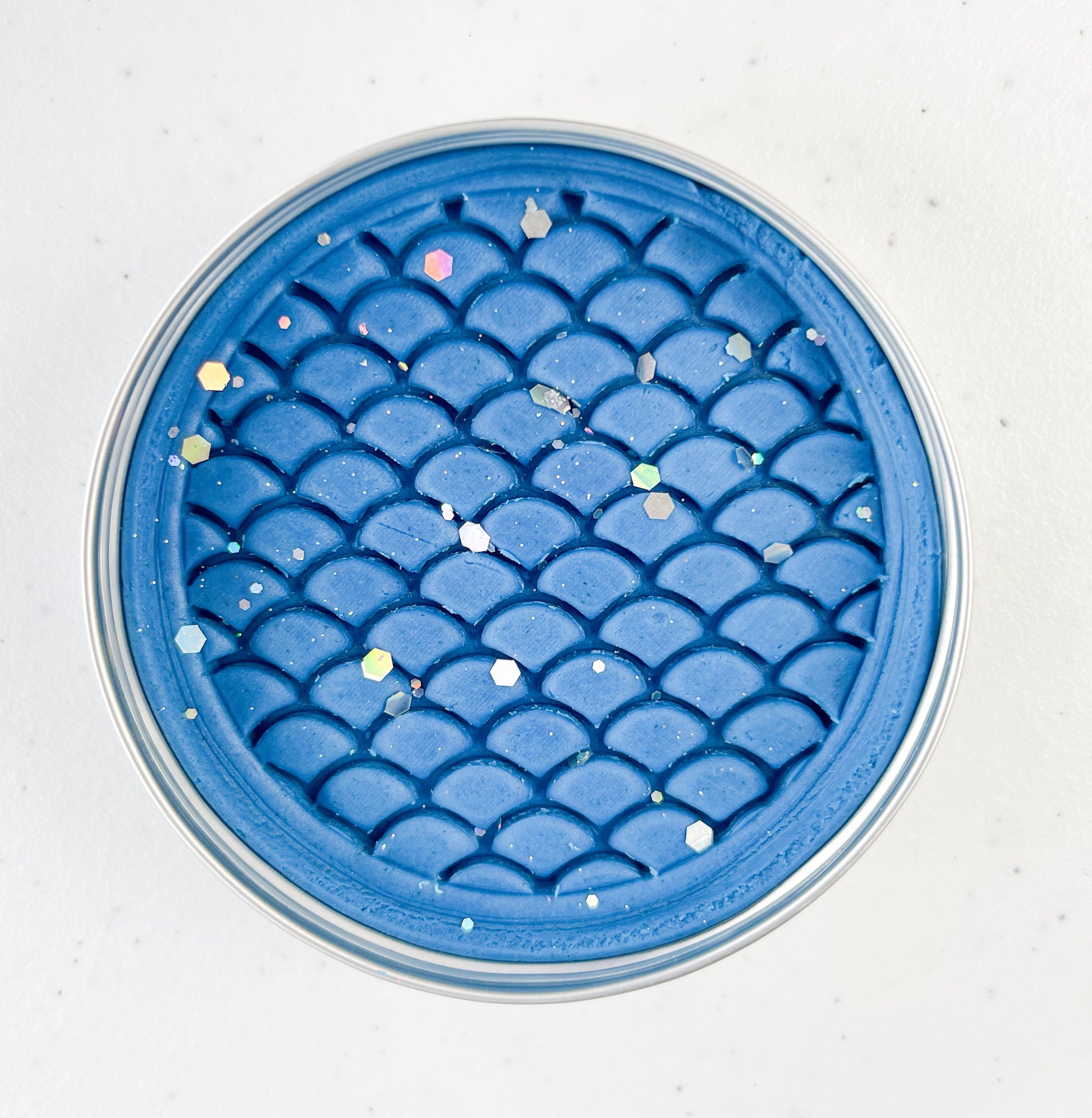 Blue textured dinosaur themed playdough tin on a white background