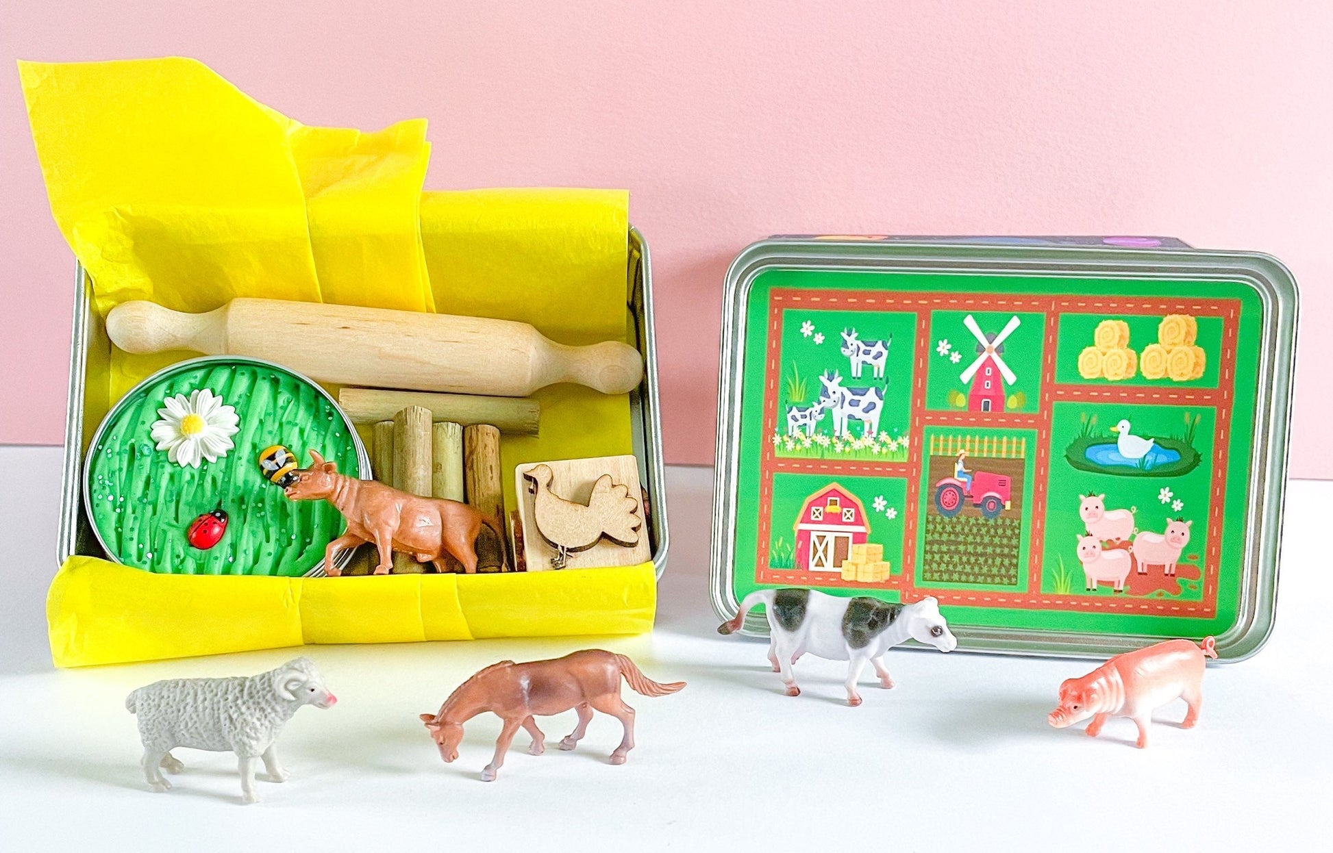 Farm Dough on the Go Activity Play Tin filled with Green Grass Farm Playdough, Farm aninmals for play scened, farm themed stamper and playdough tools and accessories wooden rolling pin. All wrapped up in a reuable metal tin with Farm stickers and wrapped in yellow tissue paper perfect for gifting.