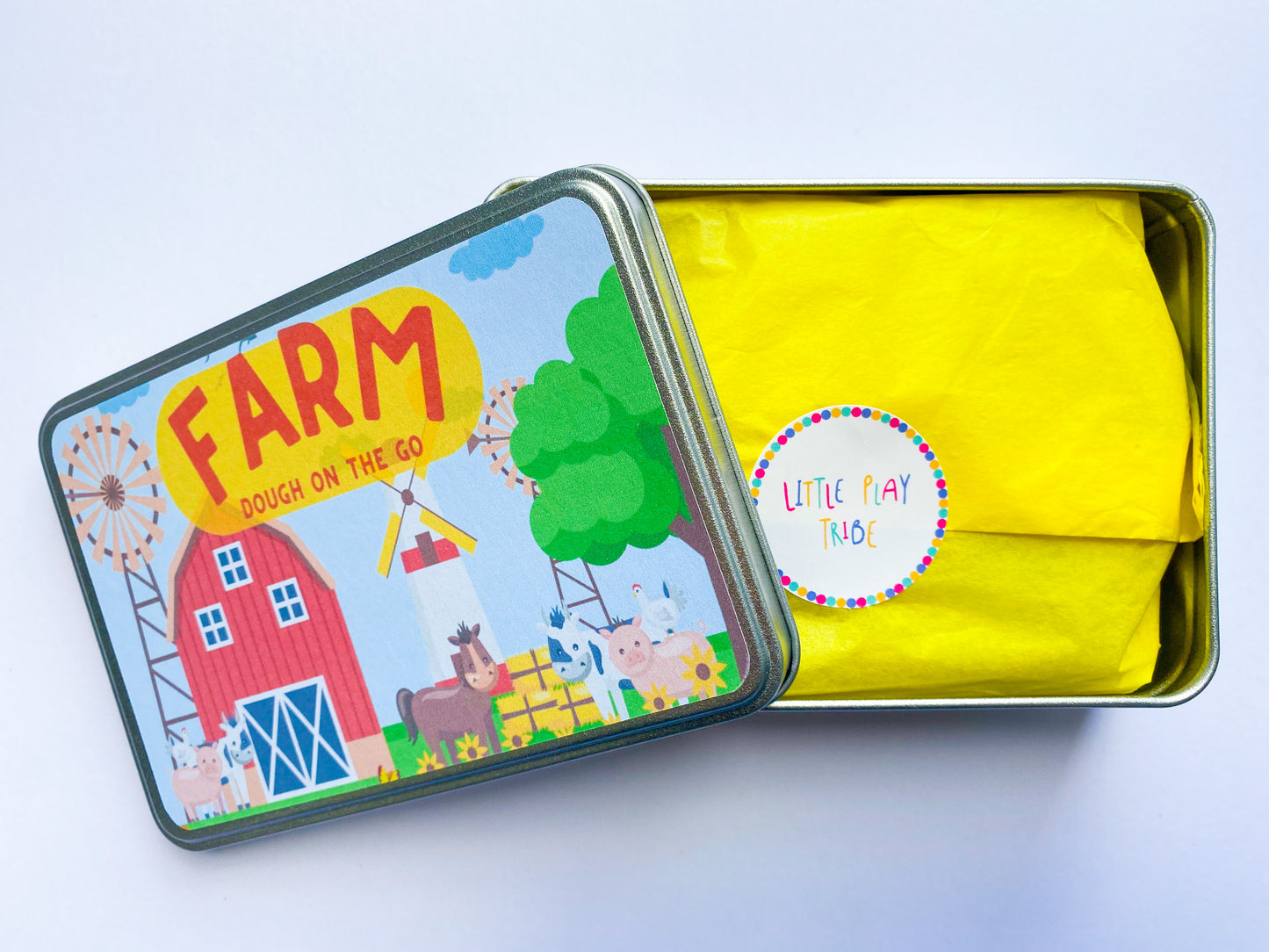 Farm Dough on the Go Activity Play Tin filled with Green Grass Farm Playdough, Farm aninmals for play scened, farm themed stamper and playdough tools and accessories wooden rolling pin. All wrapped up in a reuable metal tin with Farm stickers and wrapped in yellow tissue paper perfect for gifting.