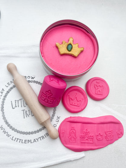 Pink Playdough in 250g maxi tub size in princess theme with hidden princesses, topped with a gold glitter crown. Shown as a grab and go dough set with Little PlayTribe Bag, Eco Princess Roller and Wooden Rolling Pin for Playdough accessories and dough tools. Playdough kit