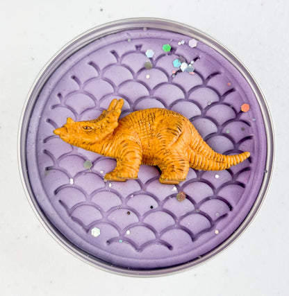 Lilac playdough tin with a yellow dinosaur toy on a white background
