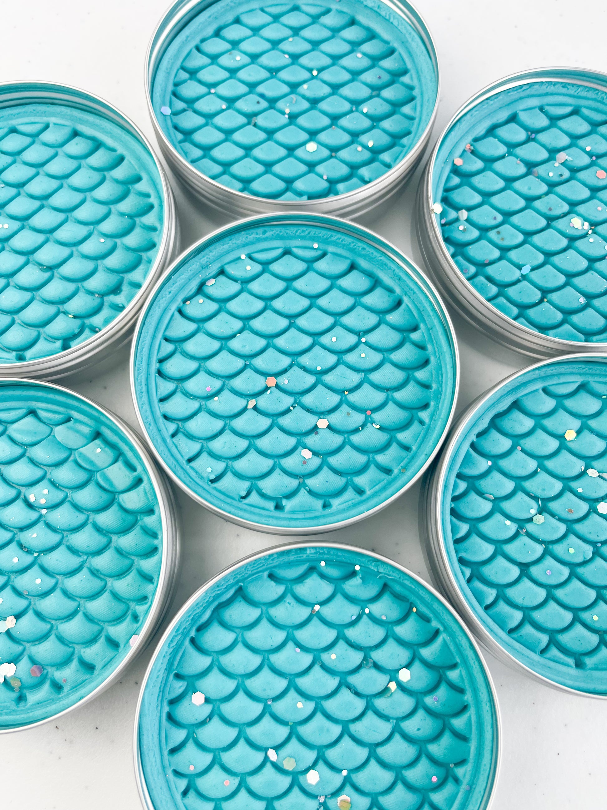 Tins of Blue playdough with mermaid scale inprint for mermaid and under the sea themed kids birthday party favours. Alternative party bag filler 