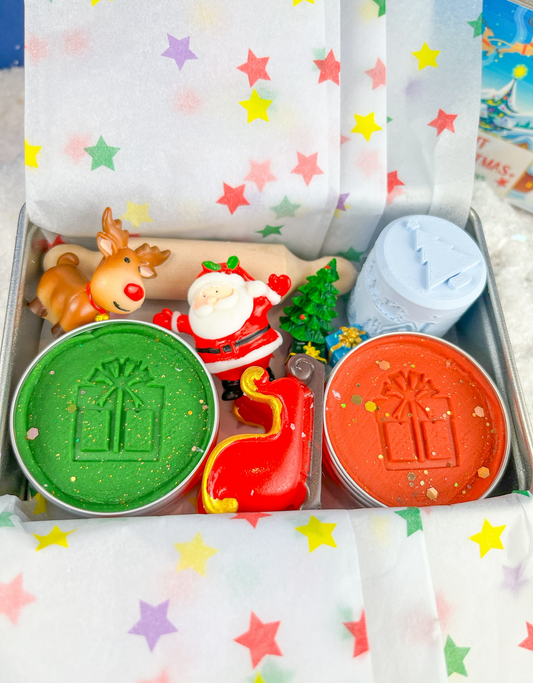 Tin filled with Christmas themed Playdough and accessories put together as a Christmas Eve gift set with red and green sensory dough, Christmas rollers and Christmas figures