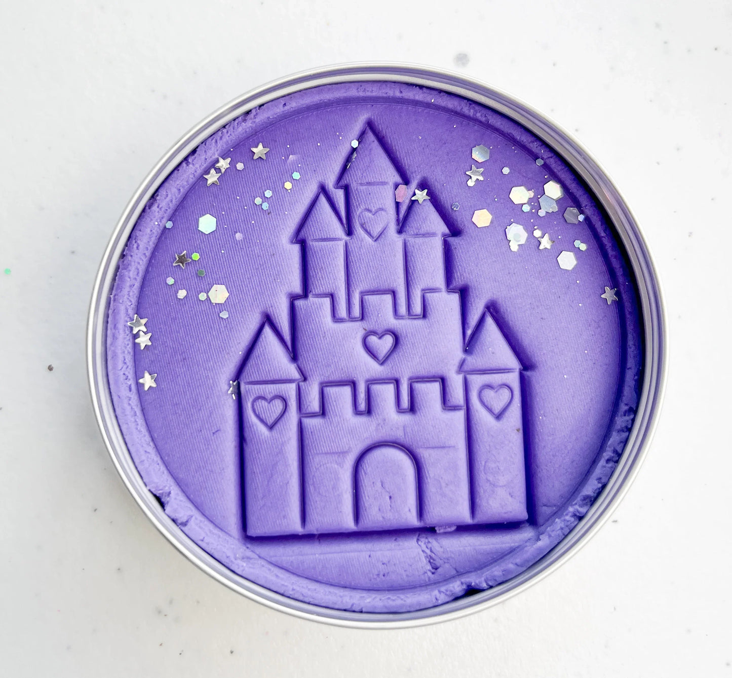 Tin of purple playdough imprinted with castle for princess themed kids birthday party favours. Eco friendly and plastic free alternative party bag fillers