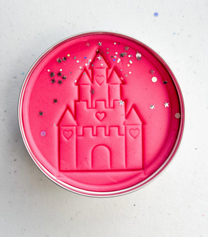 Tin of pink playdough imprinted with castle for princess themed kids birthday party favours. Eco friendly and plastic free alternative party bag fillers