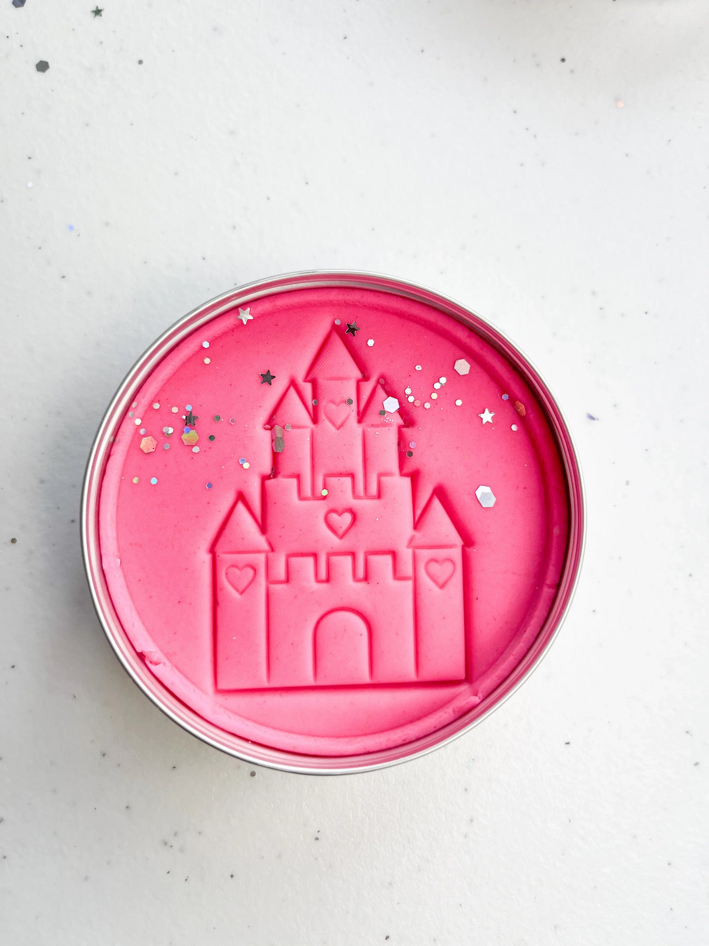 Tin of pink playdough imprinted with castle for princess themed kids birthday party favours. Eco friendly and plastic free alternative party bag fillers