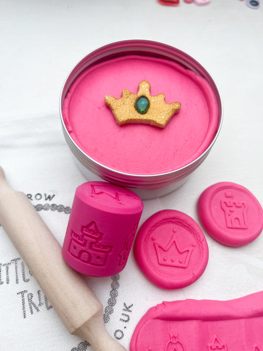 Pink Playdough in 250g maxi tub size in princess theme with hidden princesses, topped with a gold glitter crown. Shown as a grab and go dough set with Little PlayTribe Bag, Eco Princess Roller and Wooden Rolling Pin for Playdough accessories and dough tools