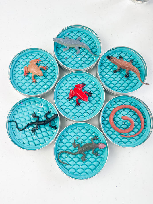 Reptile Themed Sensory Playdough Pots for Alternative Party Bag Fillers. Eco friendly, handmade playdough in a mix of colours with reptile animal characters on top. Set of blue playdough pots with various reptile figures on top