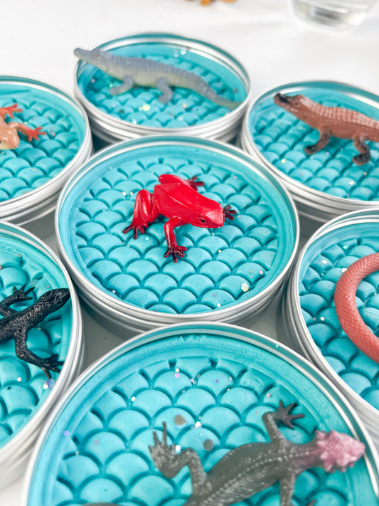 Reptile Themed Sensory Playdough Pots for Alternative Party Bag Fillers. Eco friendly, handmade playdough in a mix of colours with reptile animal characters on top. Set of blue playdough pots with various reptile figures on top