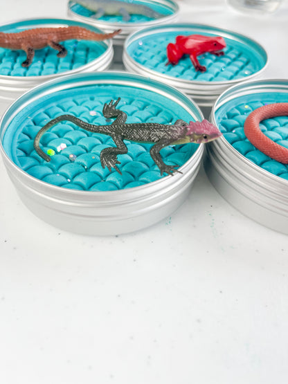 Reptile Themed Sensory Playdough Pots for Alternative Party Bag Fillers. Eco friendly, handmade playdough in a mix of colours with reptile animal characters on top. Set of blue playdough pots with various reptile figures on top