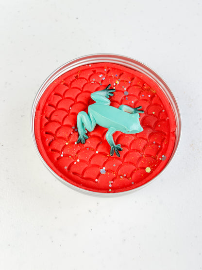 Reptile Themed Sensory Playdough Pots for Alternative Party Bag Fillers. Eco friendly, handmade playdough in a mix of colours with reptile animal characters on top. One tine of red playdough with frog figure on top