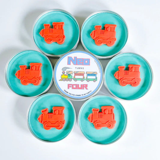 Train party bag fillers. Tins of blue playdough with red cut out train shaped playdough toppers. Personalise Neo turns 4 party bag filler label in the middle