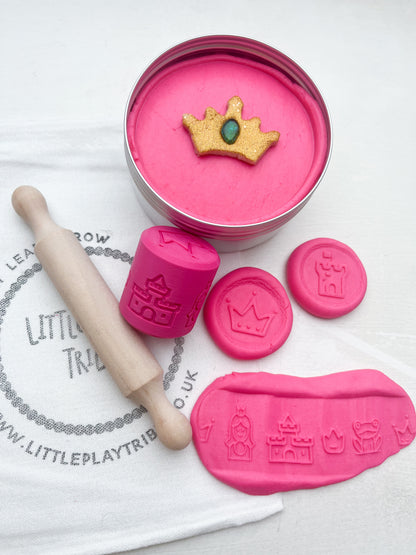 Pink Playdough in 250g maxi tub size in princess theme with hidden princesses, topped with a gold glitter crown. Shown as a grab and go dough set with Little PlayTribe Bag, Eco Princess Roller and Wooden Rolling Pin for Playdough accessories and dough tools