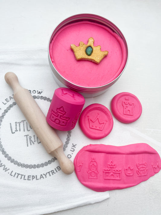 Pink Playdough in 250g maxi tub size in princess theme with hidden princesses, topped with a gold glitter crown. Shown as a grab and go dough set with Little PlayTribe Bag, Eco Princess Roller and Wooden Rolling Pin for Playdough accessories and dough tools