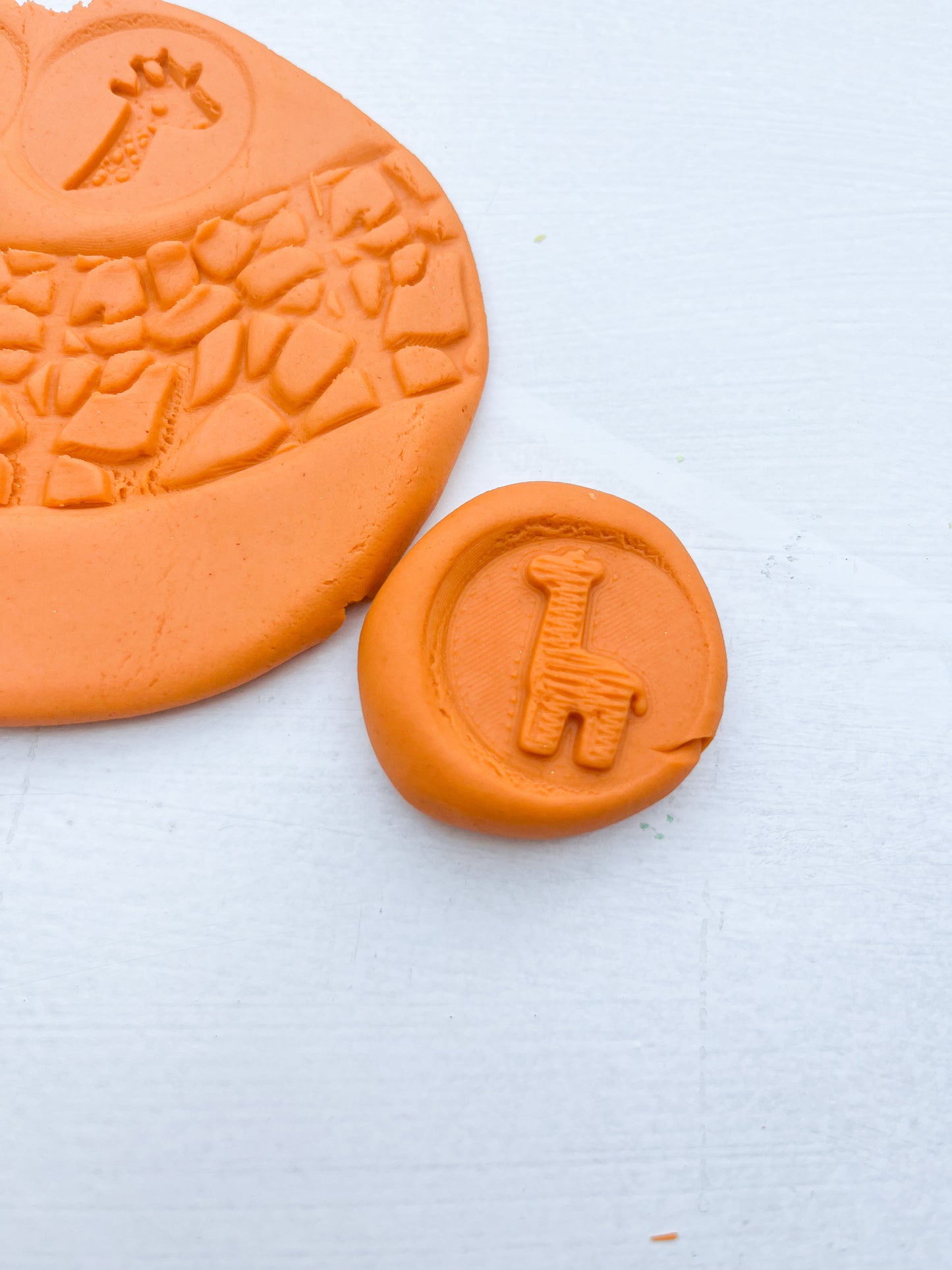 plastic free eco roller with safari themed imprints showing animal themed shapes on orange playdough with this tool